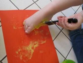 Kinder bepinseln ihre Füße mit Farbe, um Fußabdrücke zu machen