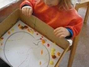 Ein Kind malt einen Kürbis mit Murmeltechnik
