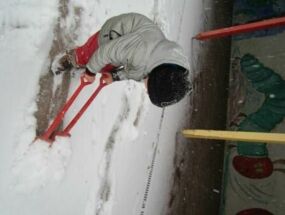 Ein Kind schiebt mit der Schaufel den Schnee weg
